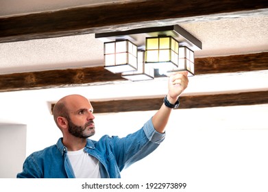 Man In Blue Shirt Changing Light Bulbs At Home