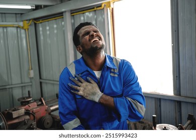 A man in a blue shirt is crying while wearing gloves. He is in a workshop or garage - Powered by Shutterstock