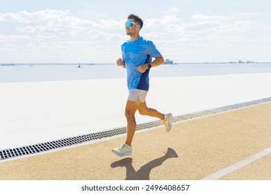 A man in a blue shirt jogs along a waterfront path, enjoying the sunny day and scenic view.

 - Powered by Shutterstock