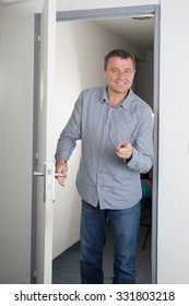 Man with a blue shirt opening a door