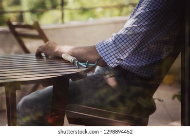 A man in a blue shirt is sitting at home on the balcony with a rake in his hands. He planted a salad. Favorite hobby - Shutterstock ID 1298894452