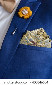 Man In Blue Suit With Brown Bow Tie, Flower Brooch, And Classic Texture Pocket Square, Close Up