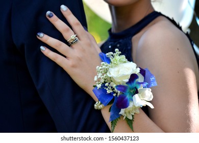 Man In Blue Suit Holding Woman Blue And White Corsage Blue Nails With Rings 