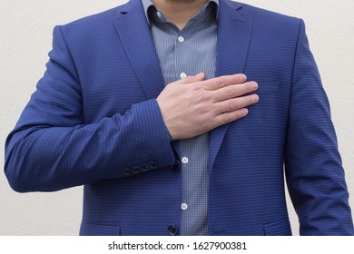 A man in a blue suit holds a palm on his heart. Patriotism concept