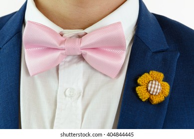 Man In Blue Suit With Pink Bow Tie, Flower Brooch, And Pink Blue Strip Pocket Square, Close Up