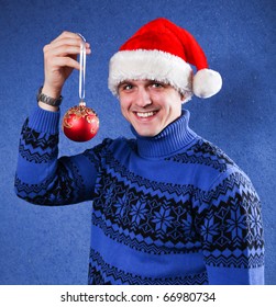 Man In Blue Sweater And Red Chrismas Hat At Blue Background