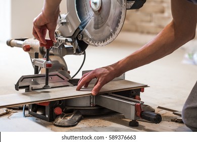 a man with a Board and miter saw closeup, concept building and repair - Powered by Shutterstock