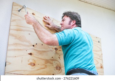 Man Boarding Up The Windows On His Home To Prepare For A Hurricane Or Tornado.  