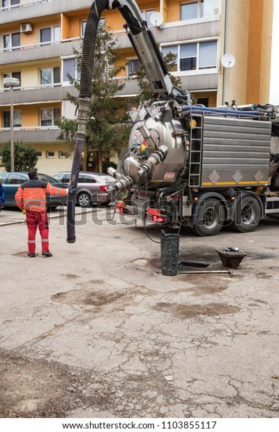 Man in boilersuit is pumping sewage with drainage\
suction sewage truck
