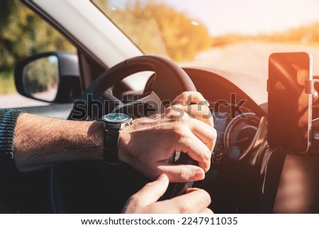 Man with both hands on steering wheel driving at sunset