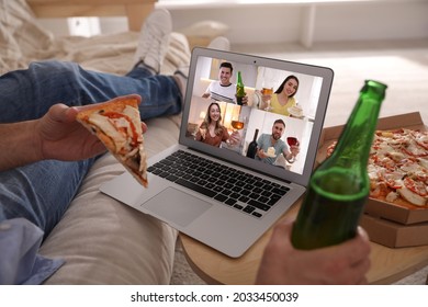 Man With Bottle Of Beer And Pizza Having Online Party Via Laptop At Home During Quarantine Lockdown, Closeup