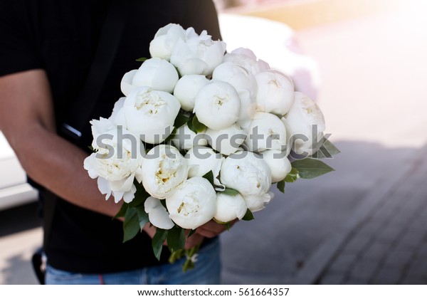 Man with bouquet of\
nice white peonys.