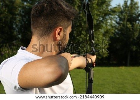 Man with bow and arrow practicing archery in park