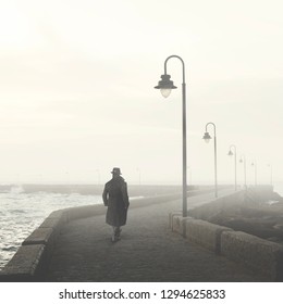 Man With Bowler And Coat Walking In A Foggy Street In Winter