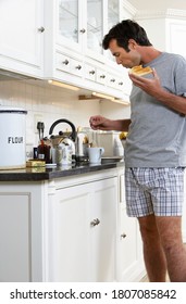 Man In Boxer Shorts Eating Toast And Making Tea