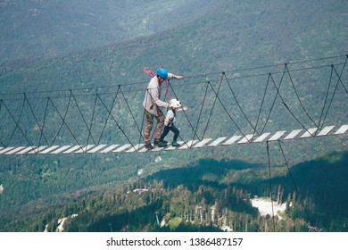 Man And Boy Walk Along The Rope Bridge. Joint Family Leisure Spending Time Together