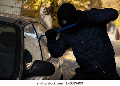 A Man Breaking In A Car Through Its Window