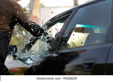 Man breaking a car's window in a million of pieces