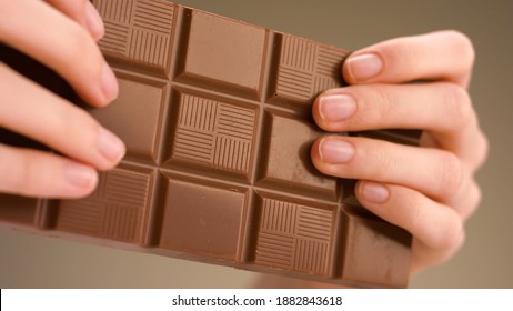 Man breaking chocolate. Stock footage. Close-up of hands breaking chocolate bar into two parts. Delicious chocolate is broken into pieces on isolated background