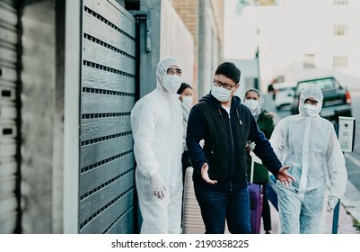 Man Breaking Covid Regulation Getting Taken Away Or Arrested By Healthcare Workers Wearing Hazmat Protective Suits. Male Removed For Not Following The Rules Or Restrictions Of Coronavirus Pandemic