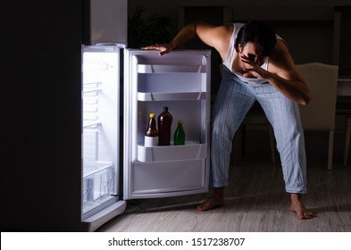 Man breaking diet at night near fridge