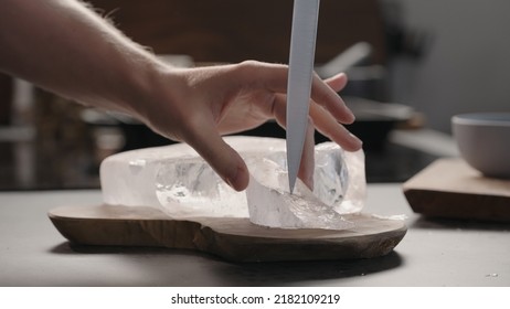 Man Breaking Ice Block With Knife On Olive Wood Board