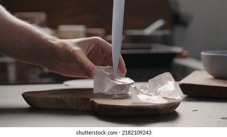 Man Breaking Ice Block With Knife On Olive Wood Board