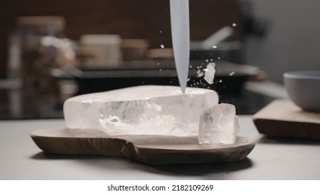 Man Breaking Ice Block With Knife On Olive Wood Board