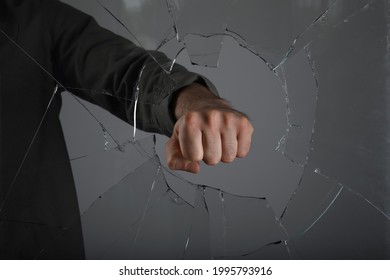 Man Breaking Window With Fist On Grey Background, Closeup