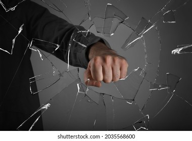 Man Breaking Window With Fist On Grey Background, Closeup