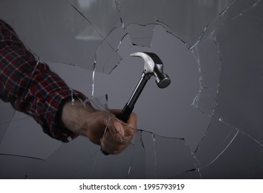 Man Breaking Window With Hammer On Grey Background, Closeup