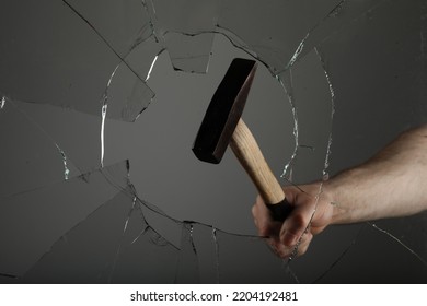 Man Breaking Window With Hammer On Grey Background, Closeup