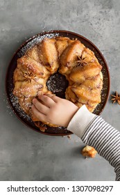 Man Breaks Off A Piece Of Monkey Bread With Cinnamon On A Wooden Table