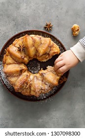 Man Breaks Off A Piece Of Monkey Bread With Cinnamon On A Wooden Table