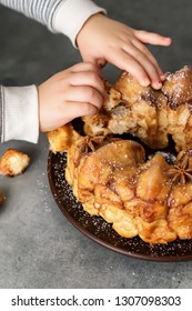 Man Breaks Off A Piece Of Monkey Bread With Cinnamon On A Wooden Table