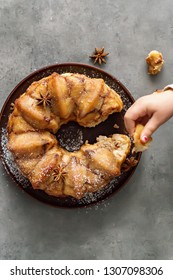 Man Breaks Off A Piece Of Monkey Bread With Cinnamon On A Wooden Table