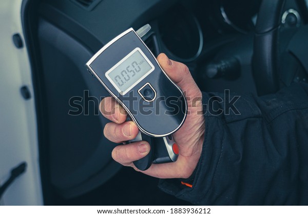 a man with a breathalyzer in the car, testing for\
alcohol and drug intoxication of the driver, selective focusing\
tinted image