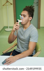 Man Breathing Into Tube Of Spirometer During Test