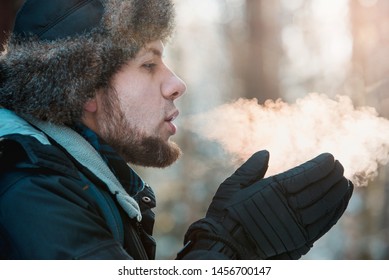 Man Breathing On Gloves In Winter Forest