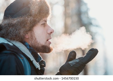 Man Breathing On Gloves In Winter Forest