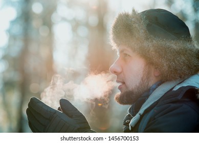 Man Breathing On Gloves In Winter Forest