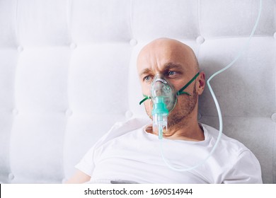 Man Breathing Through Oxygen Mask In Bed. Covid-19 Patient.