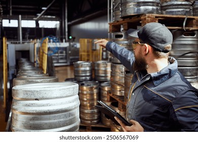 Man, brewery technologist in protective gear inspecting the production line, checking safety and quality standards. Concept of beer, brewery, manufacture, quality control - Powered by Shutterstock