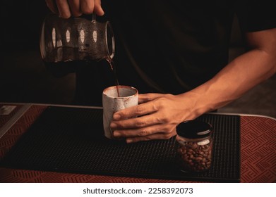 A man brewing coffee in his room. Close up of hands barista brewing a drip hot americano, pour over coffee with hot water.Practice and experiment with formulas to become a pro. - Powered by Shutterstock