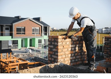 Man bricklayer installing bricks on construction site.