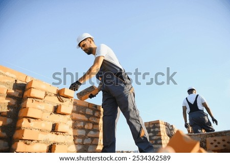 Man bricklayer installing bricks on construction site.