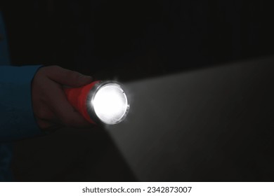 Man with bright flashlight in darkness, closeup