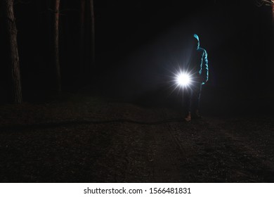 Man With Bright Flashlight In Forest At Night