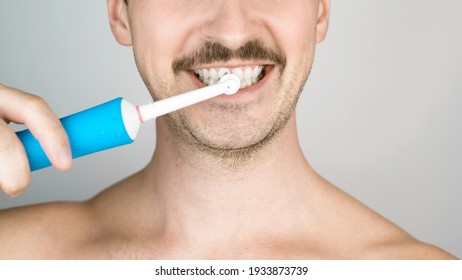 Man with bristles brushing teeth, daily hygiene procedure. Close-up portrait of man with modern electric toothbrush. Oral health - Powered by Shutterstock