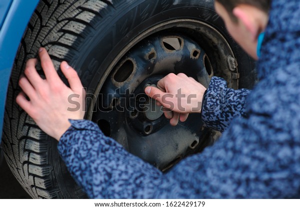 A man broke a wheel on a car and changes it on his\
own on the road.
